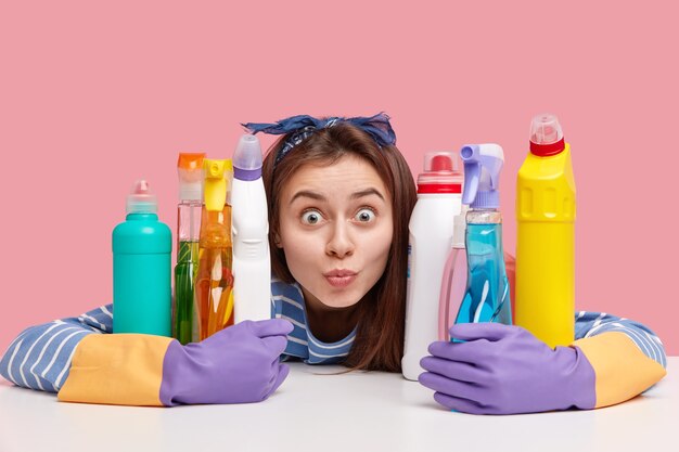 Young brunette woman sitting next to cleaning products