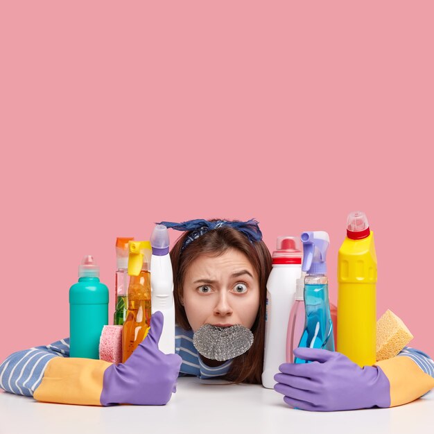 Young brunette woman sitting next to cleaning products