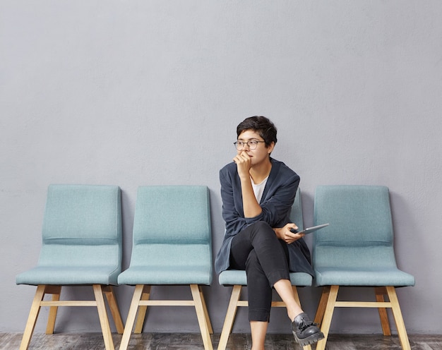 Free photo young brunette woman sitting in waiting room