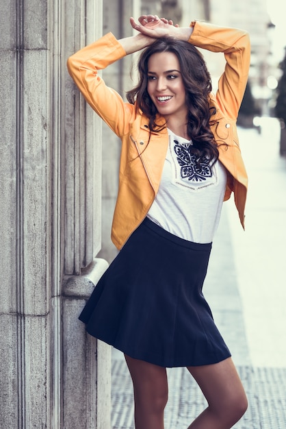 Free photo young brunette woman smiling in urban background.