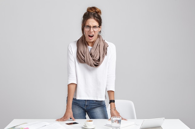 Young brunette woman standing near desk