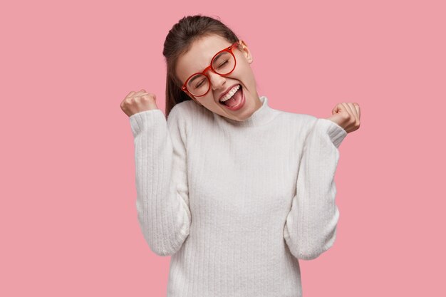 Young brunette woman wearing white sweater and red glasses