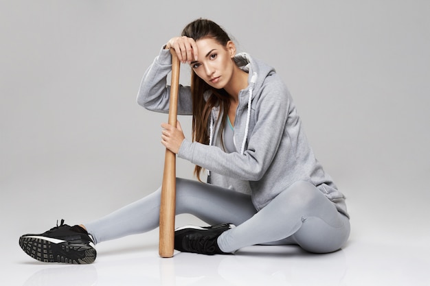 Free photo young brutal sportive woman in sportswear sitting with bit on white.