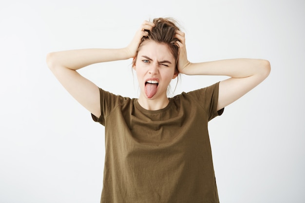 Young brutal woman showing tongue winking holding head.