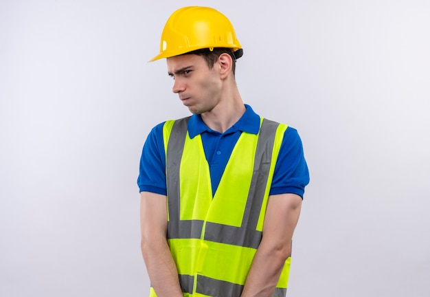 Free Photo young builder man wearing construction uniform and safety helmet looks sideways angry