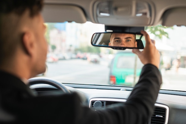 Free photo young business man arranging his rear-view mirror