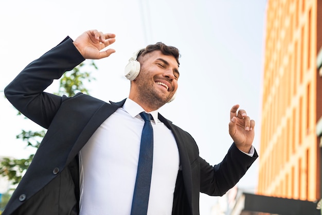 Free photo young business man listening to music and dancing