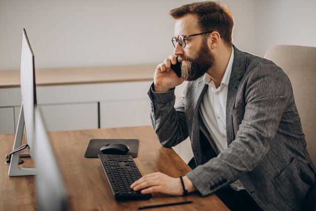 Young business man talking on phone and working on computer