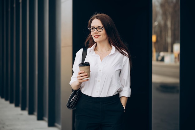 Free photo young business woman drinking coffee by the business center