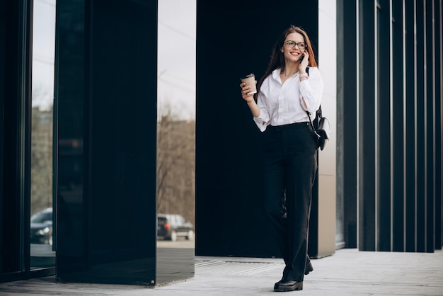 Young business woman drinking coffee by the business center