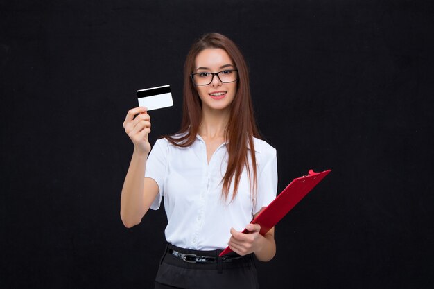 Young business woman in glasses with credit card and clipboard for notes