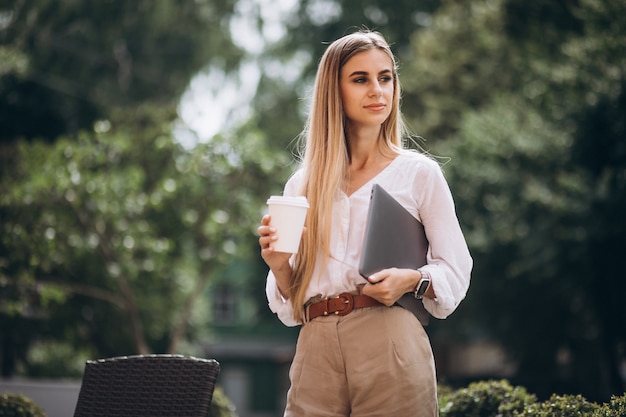 Young business woman with laptop drinking coffee outside cafe