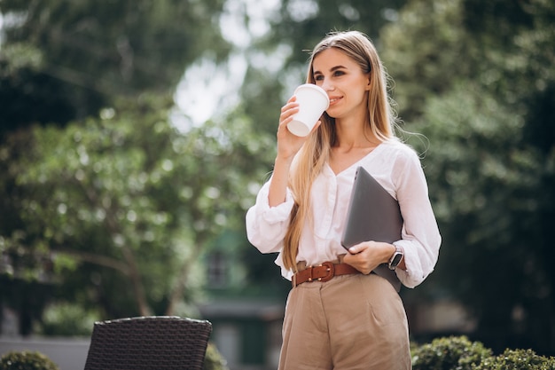 Young business woman with laptop drinking coffee outside cafe