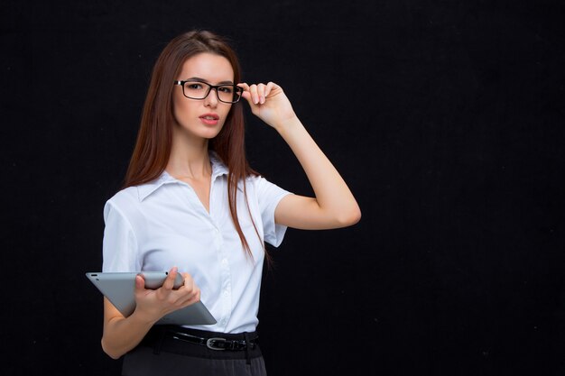 The young business woman with tablet on black wall