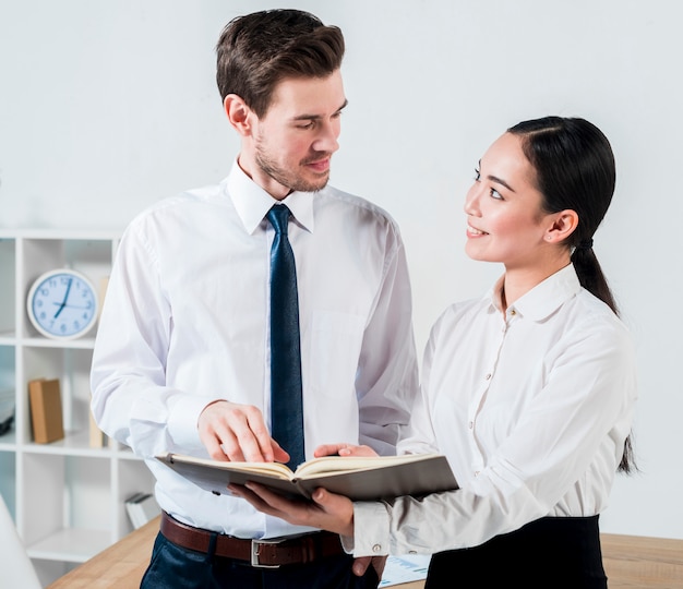 Young businessman and businesswoman discussing the project in the diary looking to each other