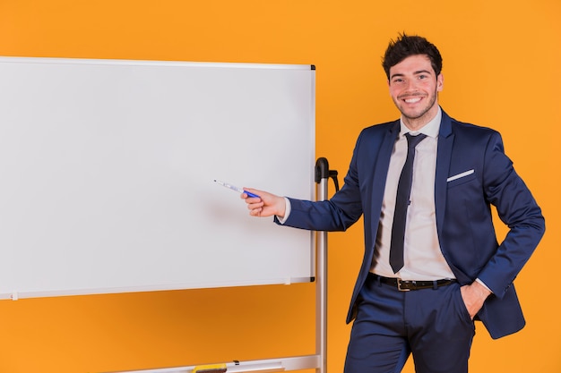 Young businessman giving presentation against an orange backdrop