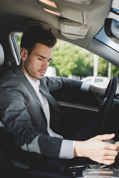 Young businessman gripping gear in the car