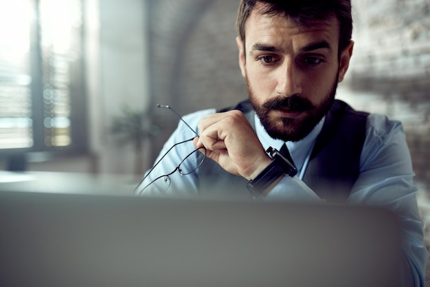 Young businessman reading an email on laptop while working in the office