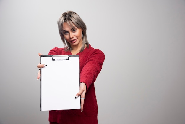 Free Photo young businessman showing clipboard on gray background.