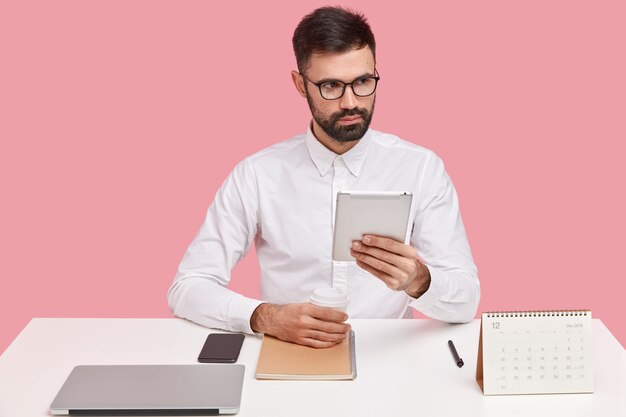 Young businessman sitting at desk with gadgets