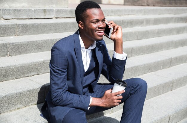 Young businessman sitting on steps holding disposable cup in hand