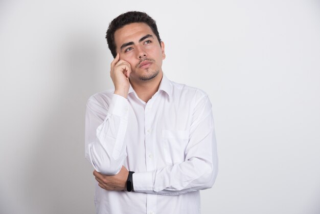 Young businessman thinking hard on white background.