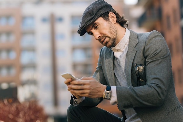 Young businessman using cell phone and reading text message on the street