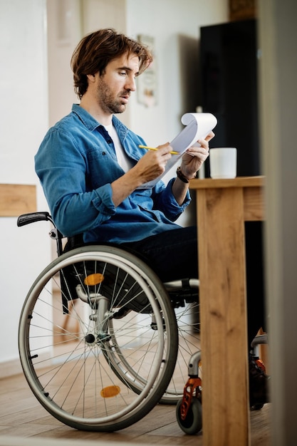 Young businessman in wheelchair going through paperwork while working at home.