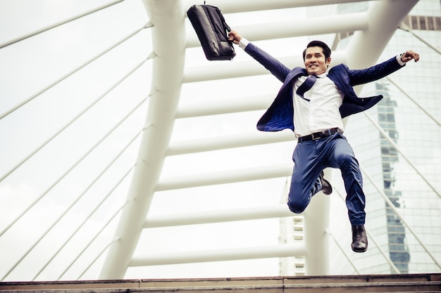 Young businessman with a briefcase running in a city street hurry up to go work.