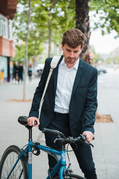 Young businessman with his backpack standing with bicycle on street