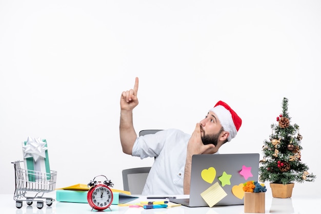 Young businessman with surprised facial expression in office celebrating christmas pointing up