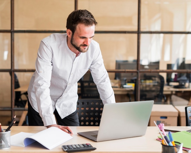 Free photo young businessman working with laptop at office