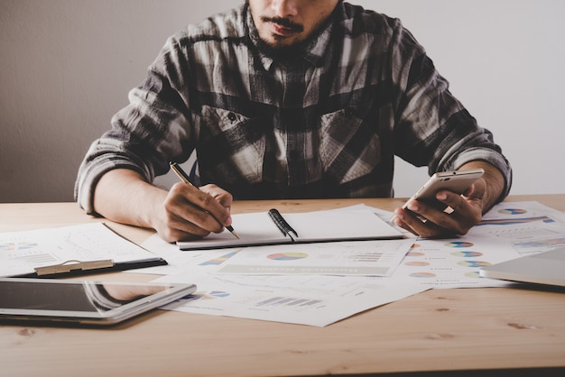 Free photo young businessman writes in a notebook while working analysis business data in office.