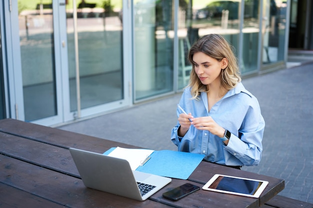 Young businesswoman attend online video conference writing down working taking notes in her document