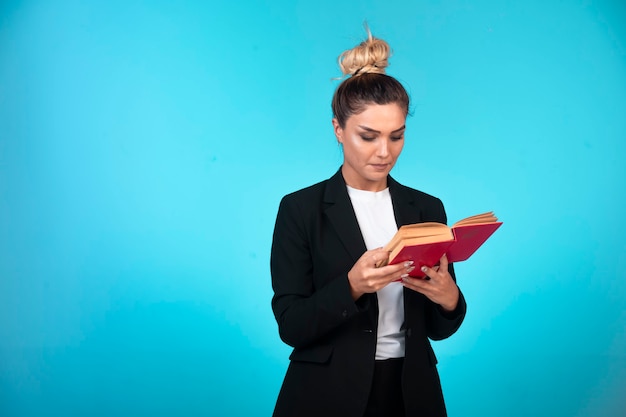 Young businesswoman in black blazer holding a taskbook and checking the meetings.