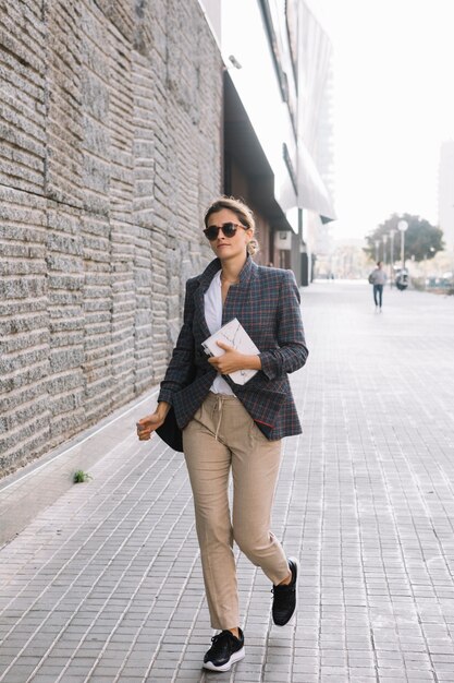 Young businesswoman holding diary in hand walking on street