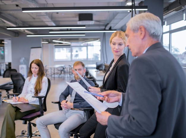 Free photo young businesswoman looking at senior businessman pointing documents in his hand