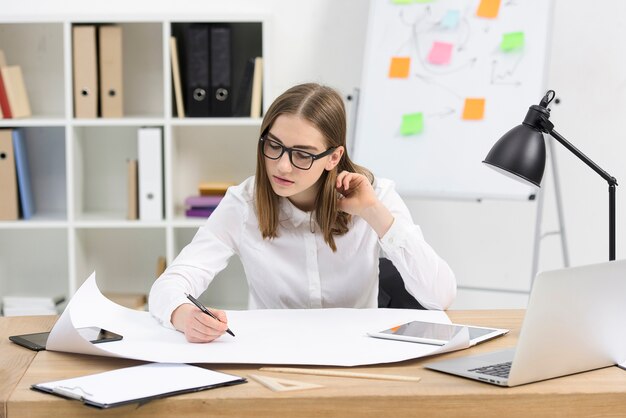 Young businesswoman planning the project on white paper in the office