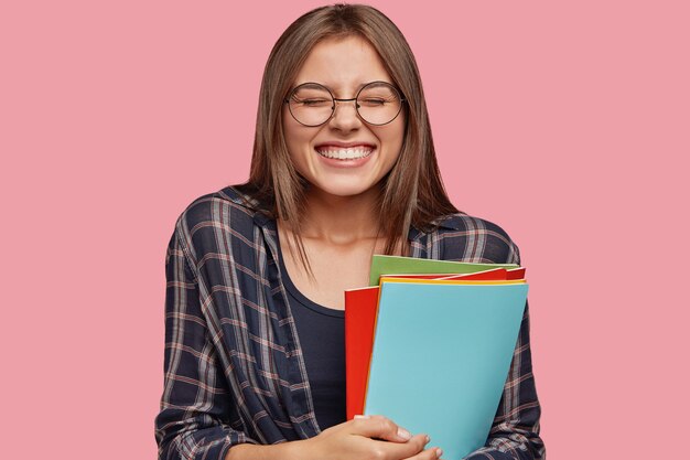 young businesswoman posing against the pink wall with glasses