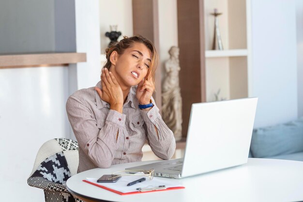 Young Businesswoman Suffering From Neckache Massaging her Neck While Sitting at Her Working Place in Home Office