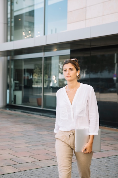 Free photo young businesswoman walking in front of corporate building