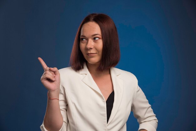 Young businesswoman in white blazer showing something.