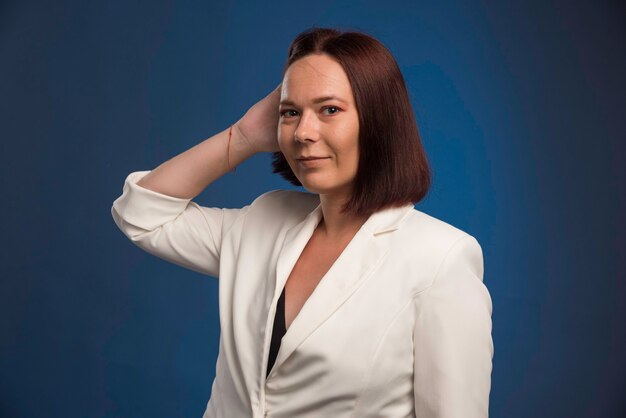 Young businesswoman in white blazer smiling secretly. 