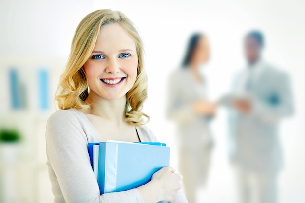 Free photo young businesswoman with co-workers blurred background