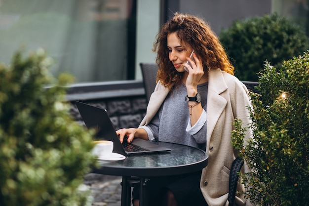 Free photo young businesswoman working on a computer outside the cafe