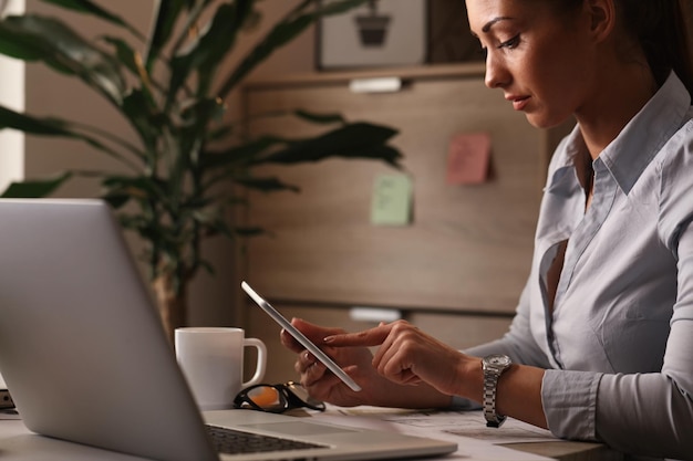 Free Photo young businesswoman working on touchpad and surfing the net at her office desk