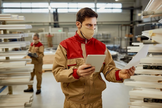 Young carpenter using digital tablet while going through checklist in a workshop