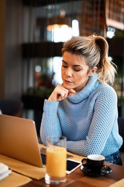 Free photo young casual businesswoman holding hand on chin working on a computer and contemplating on coffee break