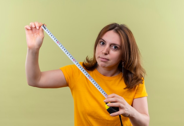 Young casual woman holding tape meter and  on isolated green wall