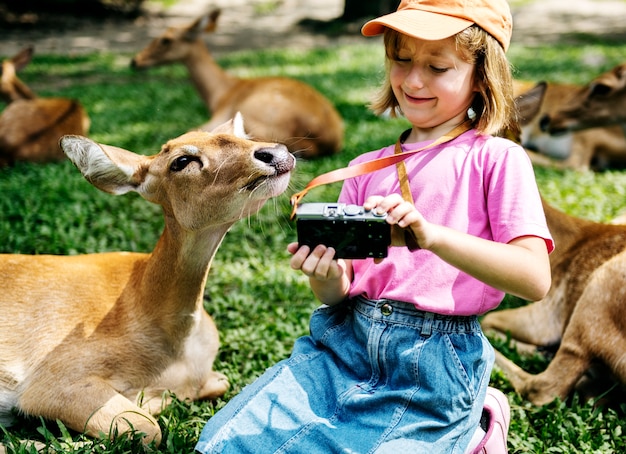 Young caucasian girl taking selfie with deers at the zoo